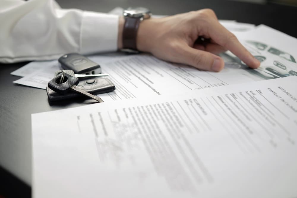 A man signing a car contract, highlighting the new car insurance law in Virginia effective 2024.