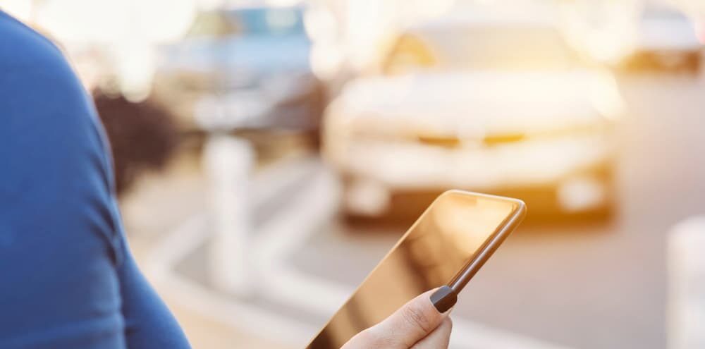 View of a smart phone in the hands of a female requesting a ride share in Woodbridge